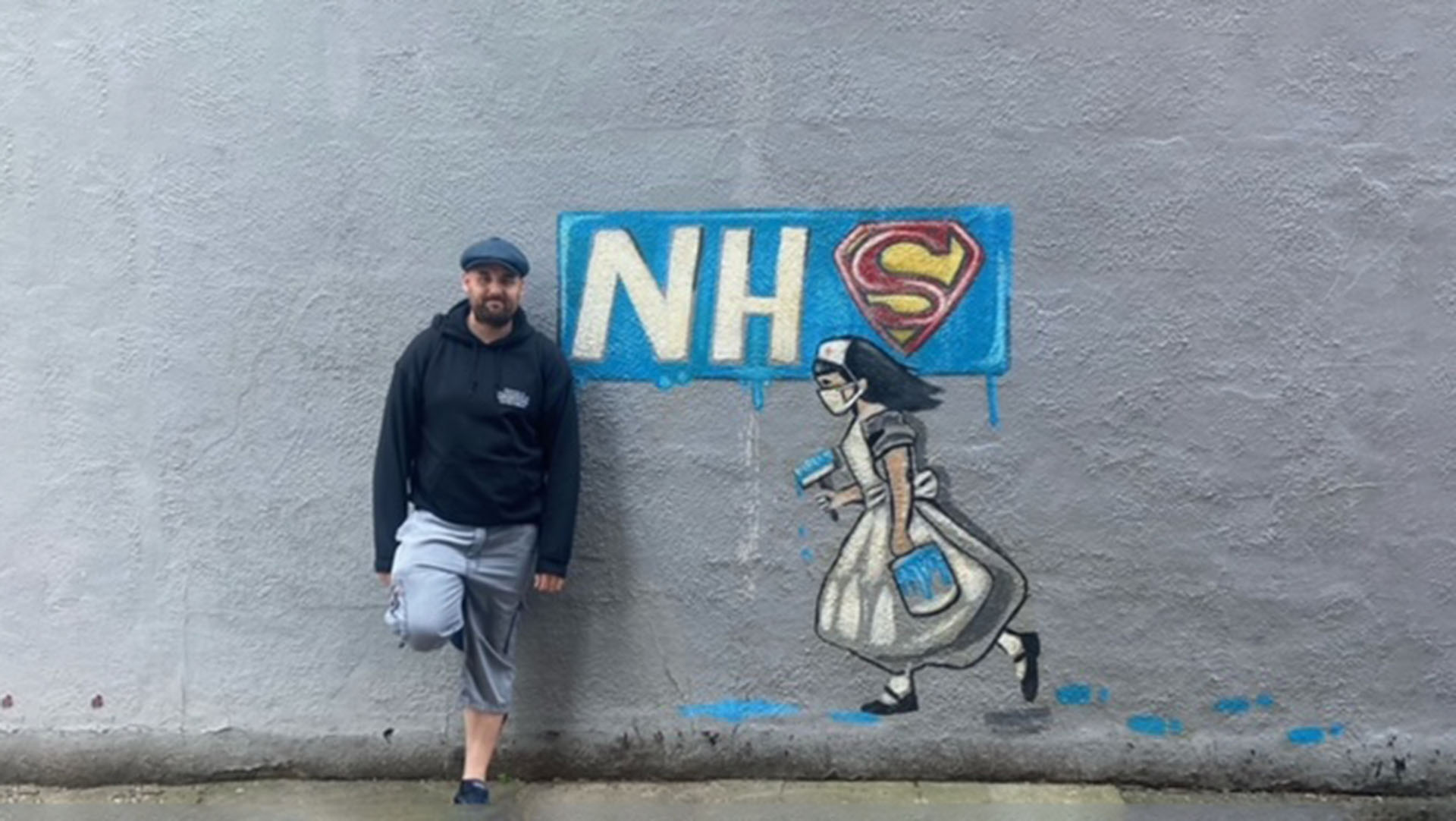 Luke next to NHS mural