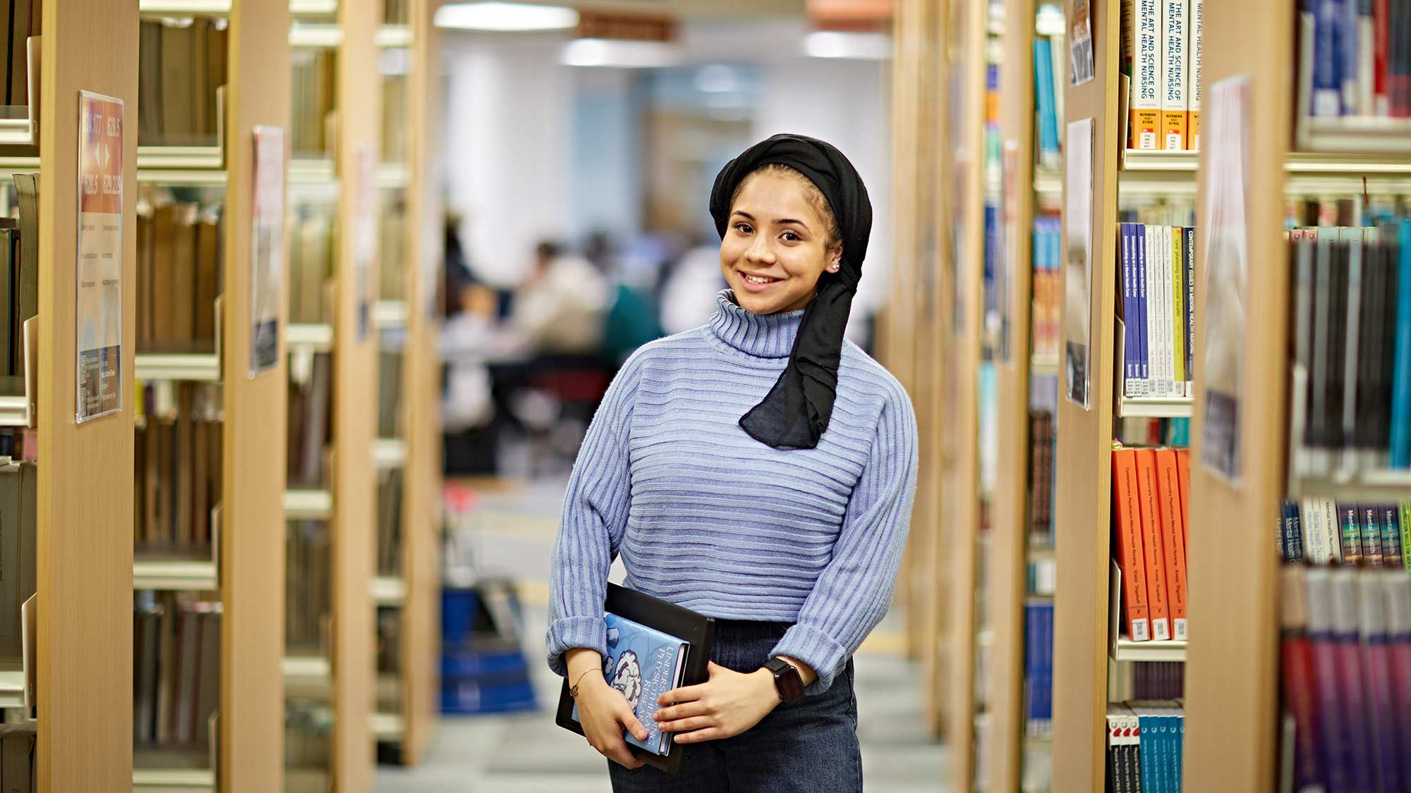 A student stood between shelves in the library