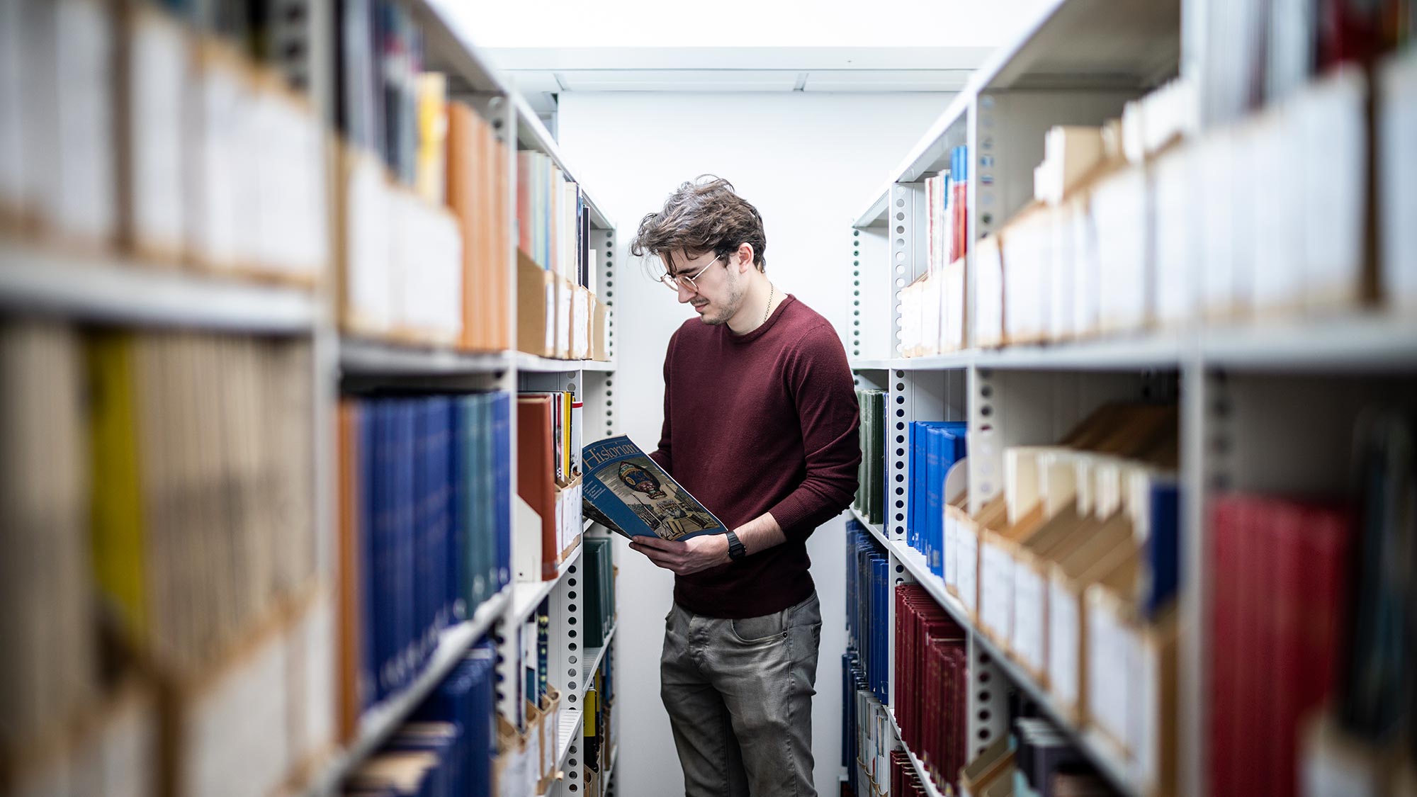 Tom, who is studying for a PhD with us, looks as at a book in the library