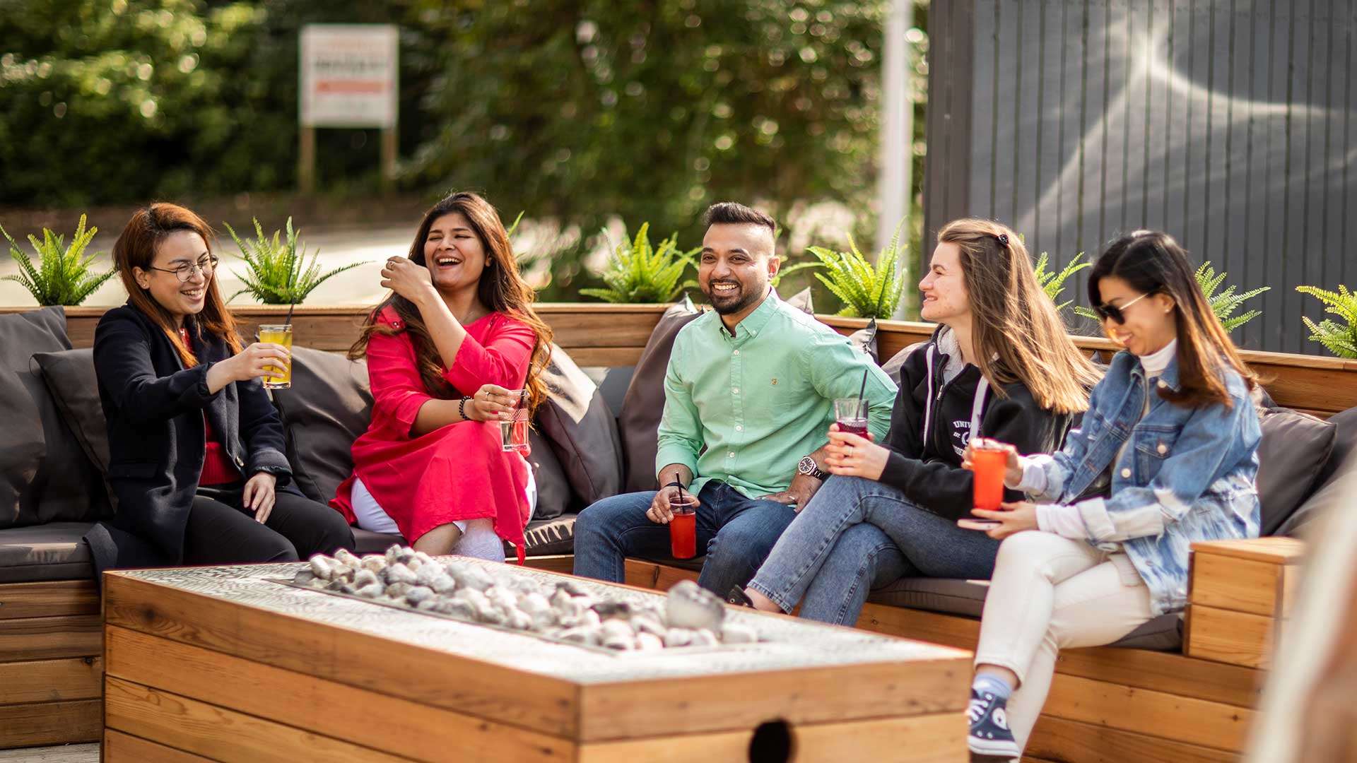 A group of student sharing drinks at a outdoor table
