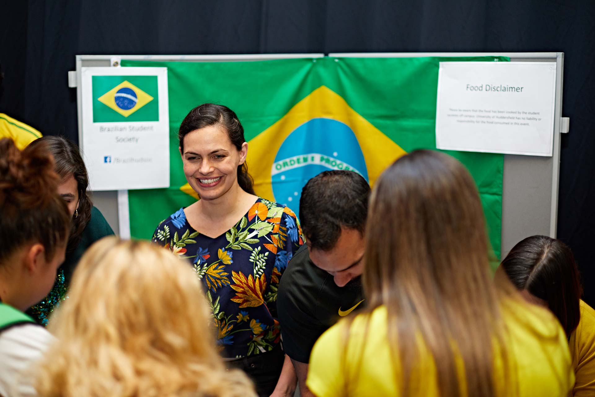 A photograph of students in the Brazilian society serving food at a stall.
