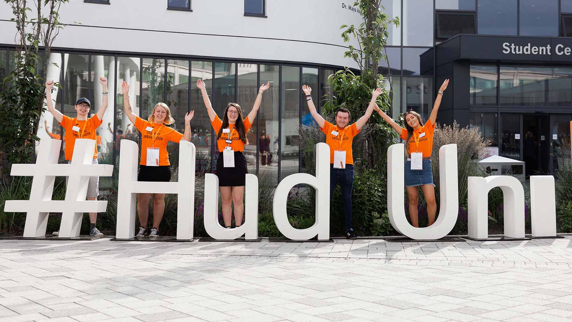 A group of ambassadors in from of giant Hud Uni letters outside Student Central