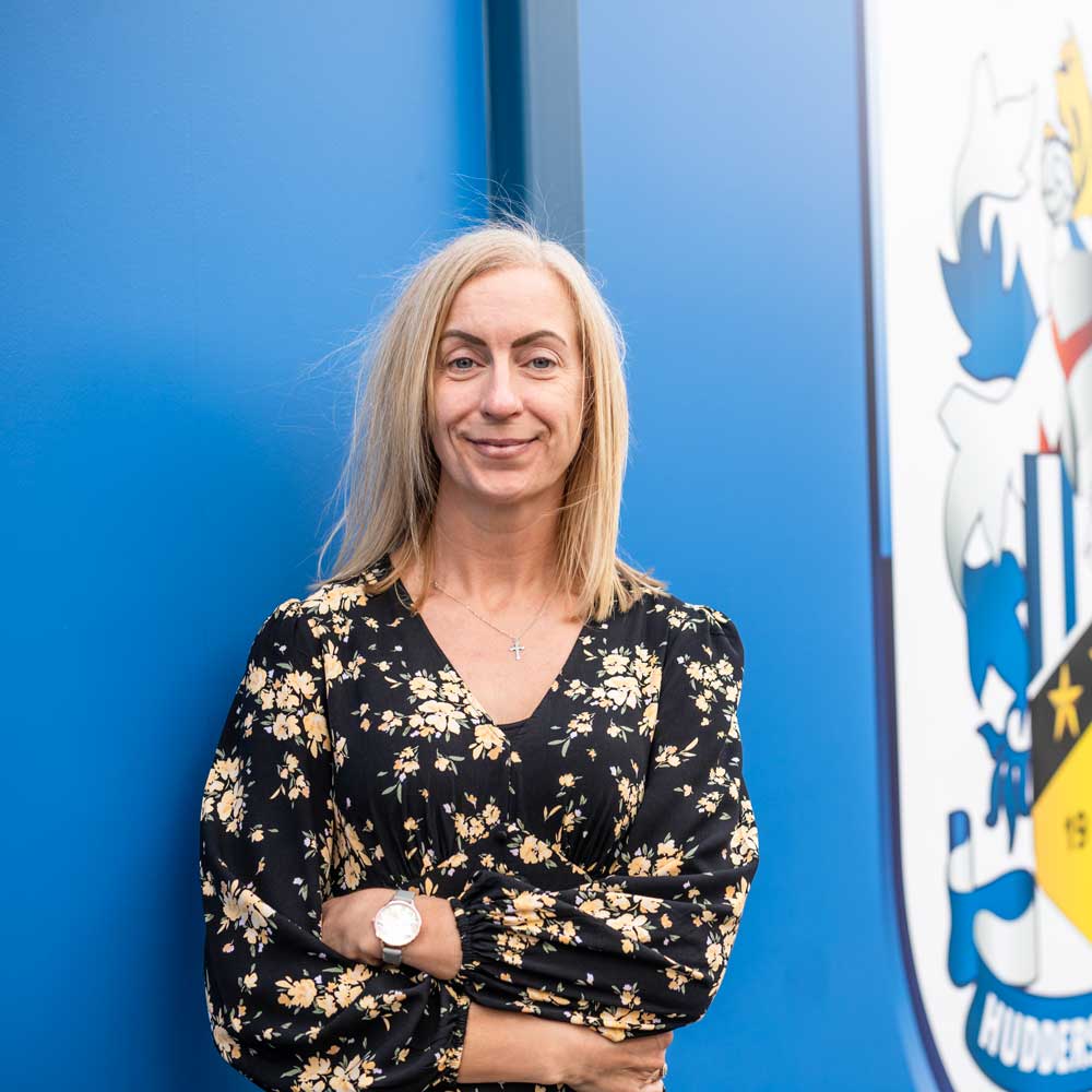 a picture of zoe standing in front of the huddersfield town logo